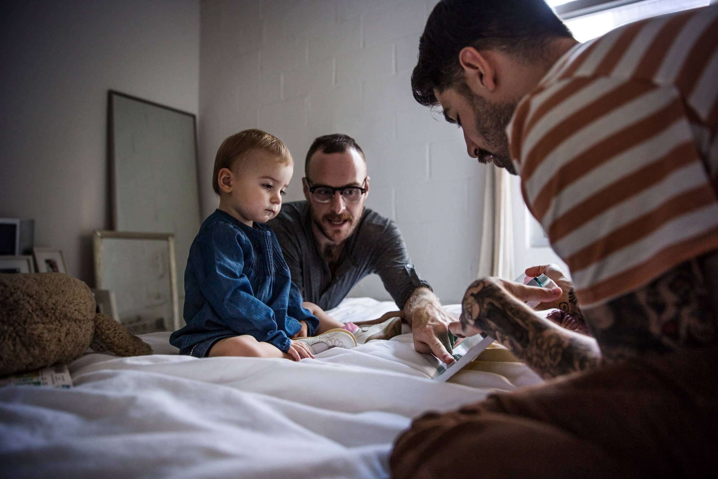 A family looking at a tablet together on a bed