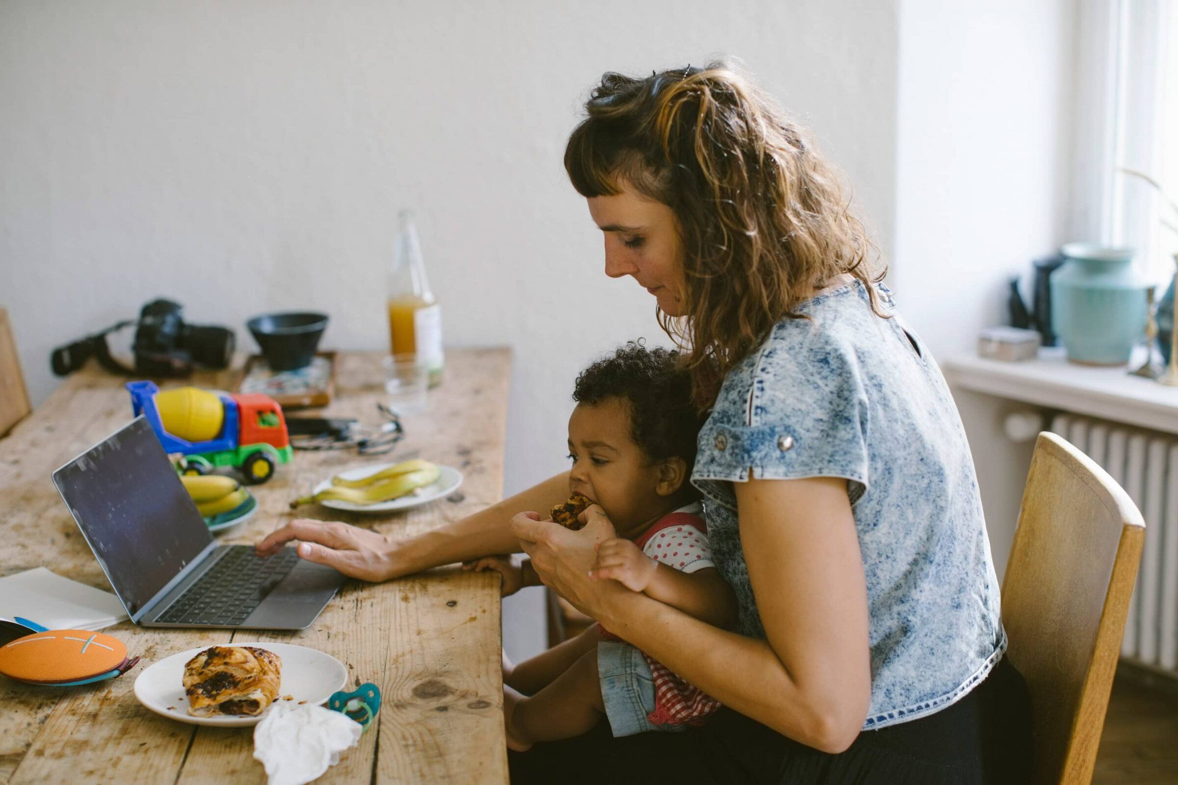 A mother and her young son at the kitchen table with a laptop