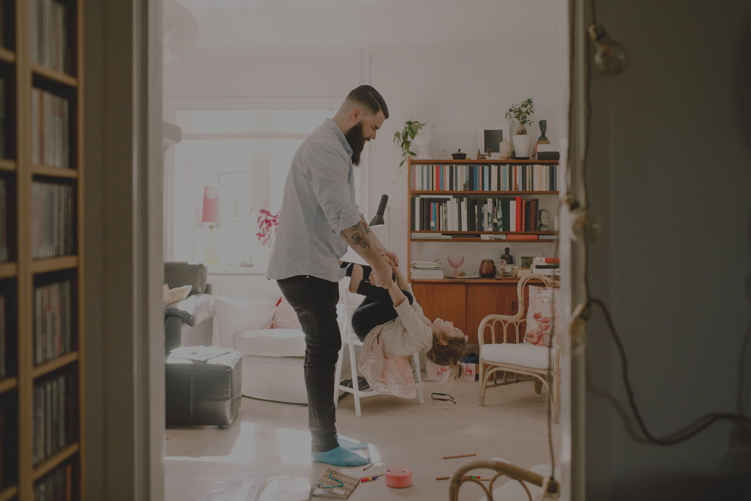 A man tidying up a bright, airy living room with bookshelves